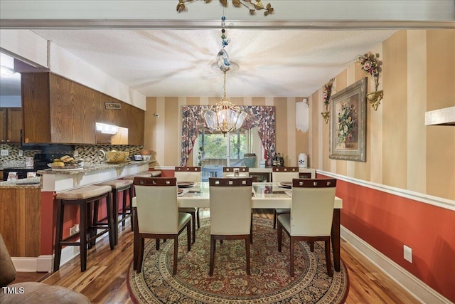 dining area featuring a textured ceiling, wood finished floors, and a notable chandelier