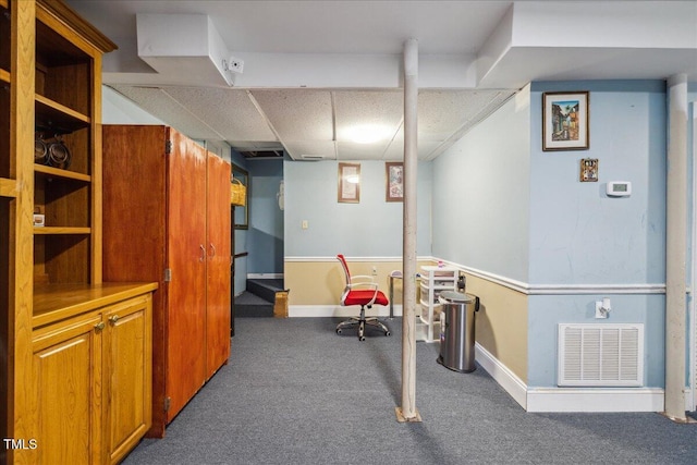 finished below grade area with carpet floors, baseboards, visible vents, and a drop ceiling