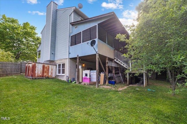 back of property with fence, a chimney, a sunroom, stairs, and a lawn