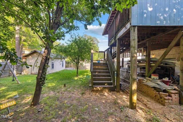 view of yard with fence, stairs, an outbuilding, and a deck