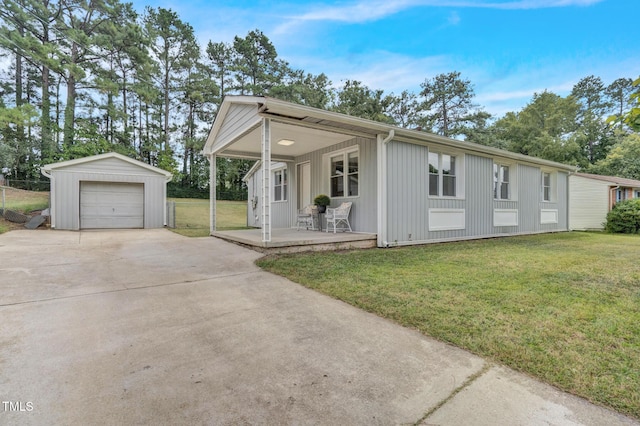view of front of house featuring a front lawn, fence, driveway, a porch, and an outbuilding