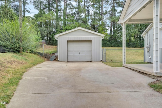 detached garage featuring concrete driveway and fence