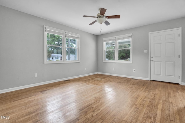 spare room with baseboards, ceiling fan, light wood-style flooring, and visible vents