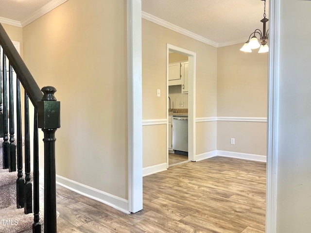 stairway featuring an inviting chandelier, ornamental molding, baseboards, and wood finished floors