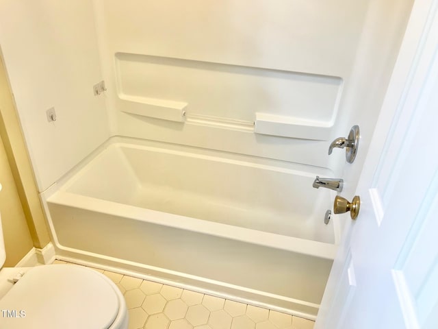 bathroom featuring tile patterned flooring, tub / shower combination, and toilet