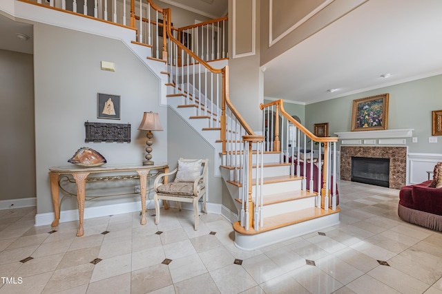 stairs with crown molding, baseboards, a glass covered fireplace, and tile patterned flooring