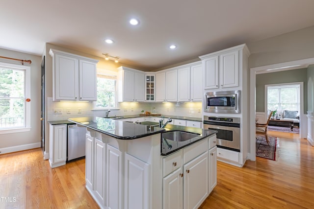 kitchen featuring light wood-style floors, a sink, white cabinetry, and appliances with stainless steel finishes