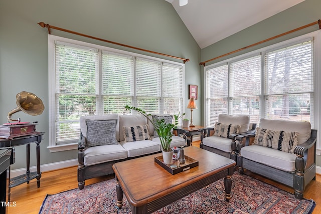 living area with baseboards, light wood-style flooring, and lofted ceiling