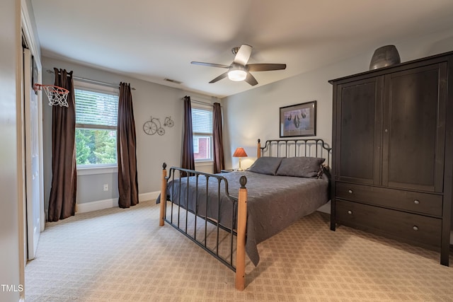bedroom with baseboards, visible vents, ceiling fan, and light colored carpet