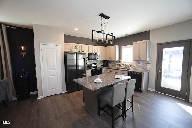 kitchen featuring a breakfast bar area, a center island, tasteful backsplash, a sink, and black appliances