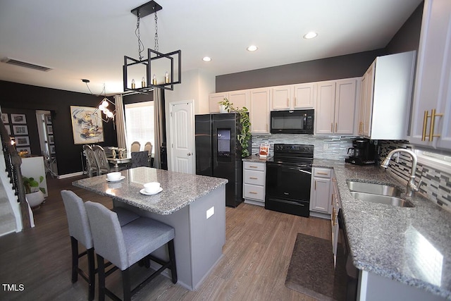 kitchen with backsplash, visible vents, a sink, black appliances, and an inviting chandelier