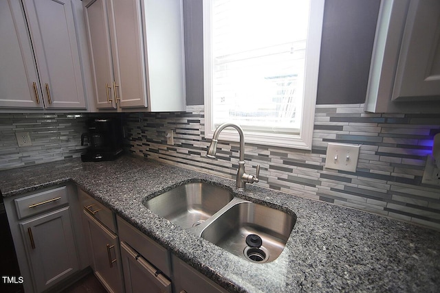 kitchen featuring backsplash, gray cabinets, a sink, and dark stone counters