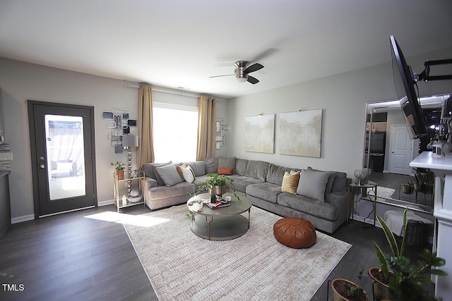 living area with baseboards, ceiling fan, and wood finished floors