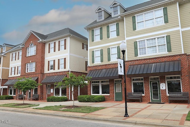 townhome / multi-family property with brick siding, a standing seam roof, and metal roof