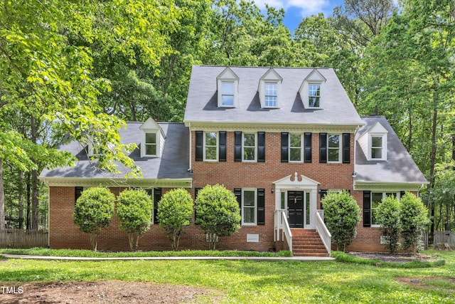view of front of house featuring brick siding, fence, and a front lawn
