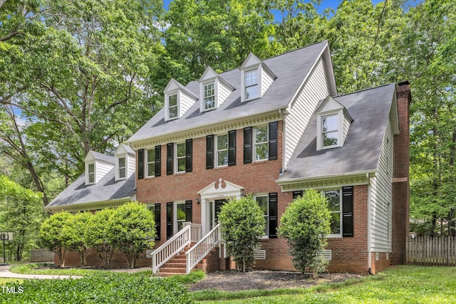 view of front facade featuring fence, a chimney, and brick siding
