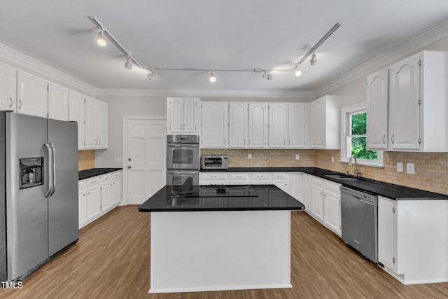 kitchen with track lighting, a sink, appliances with stainless steel finishes, and white cabinets