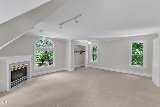 unfurnished living room featuring a premium fireplace, light colored carpet, and a healthy amount of sunlight