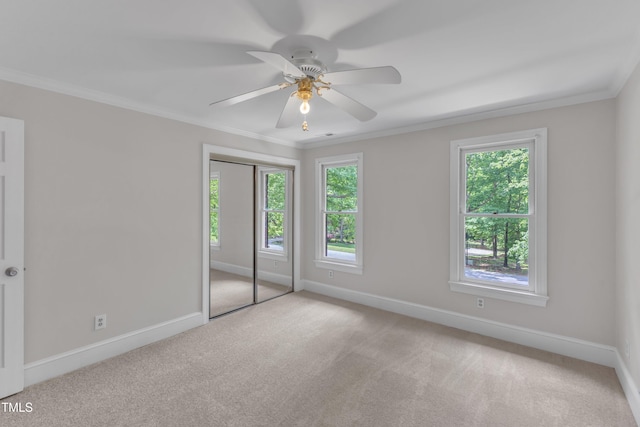 unfurnished bedroom featuring a ceiling fan, baseboards, a closet, ornamental molding, and carpet flooring