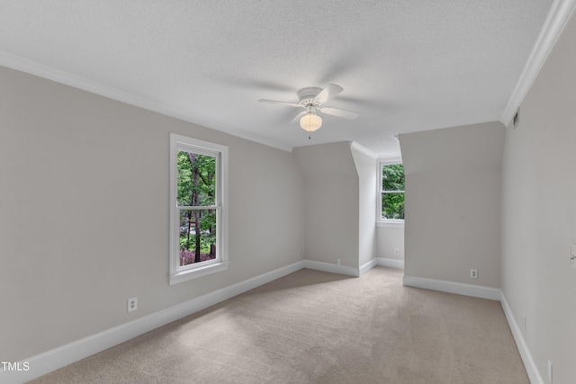 spare room featuring plenty of natural light, ornamental molding, a ceiling fan, and light colored carpet