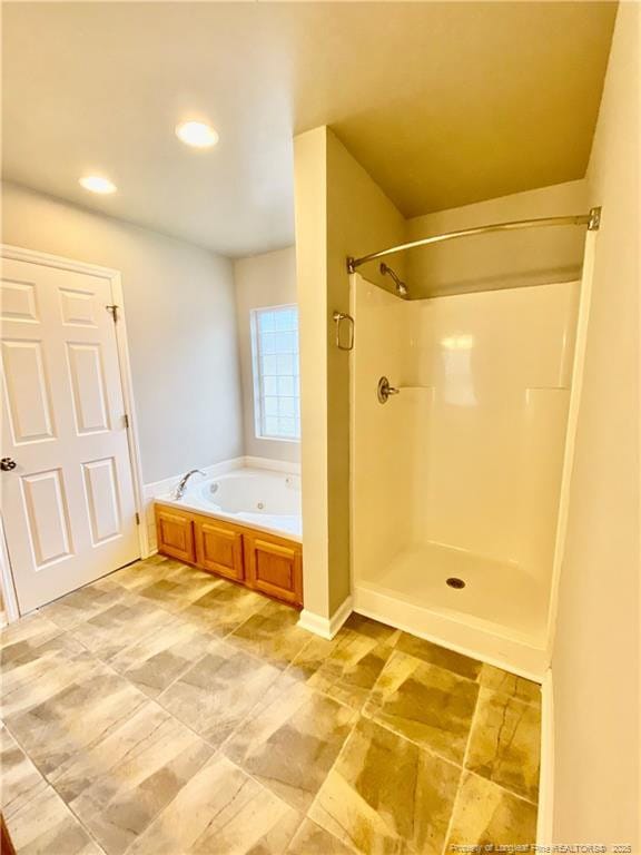bathroom with recessed lighting, a garden tub, and a shower