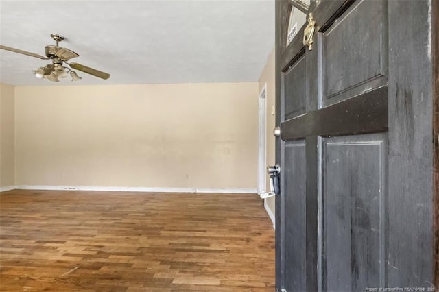 unfurnished room featuring a ceiling fan, baseboards, and wood finished floors