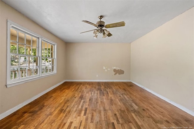 unfurnished room with a ceiling fan, baseboards, and wood finished floors