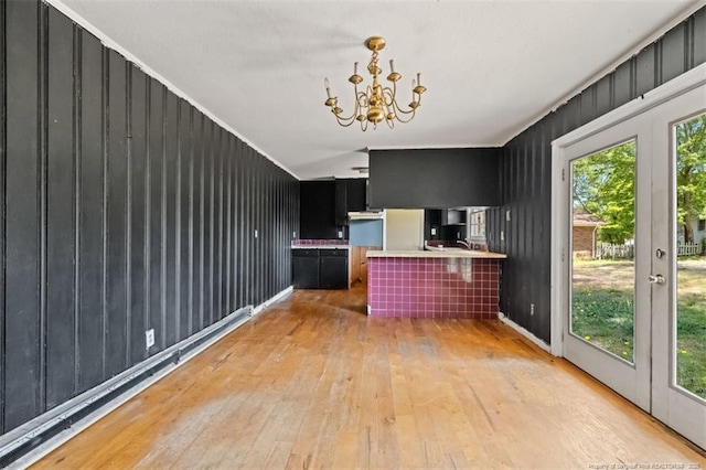 kitchen with crown molding, dark cabinetry, wood-type flooring, and a chandelier