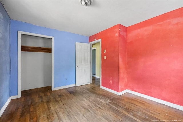 unfurnished bedroom featuring baseboards, a closet, and hardwood / wood-style floors