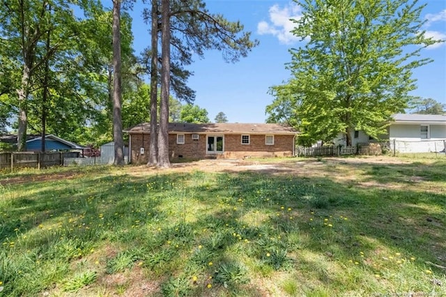 back of property featuring a yard, brick siding, and fence