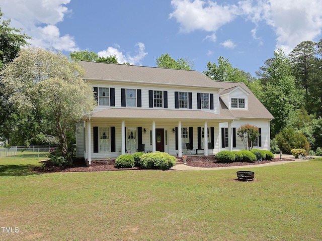 colonial house featuring a porch, fence, and a front yard