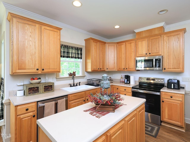 kitchen featuring stainless steel appliances, ornamental molding, a sink, wood finished floors, and light countertops
