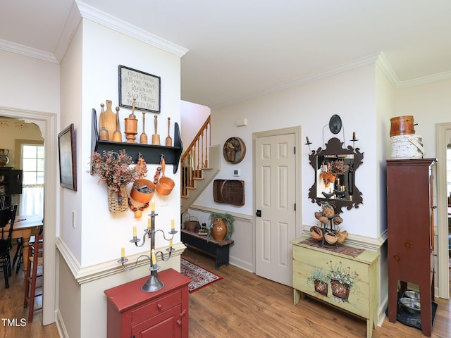 foyer entrance featuring crown molding, wood finished floors, and stairs