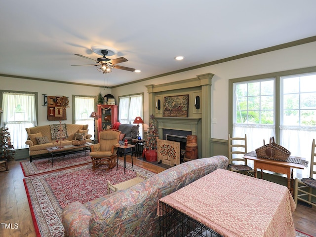 living room with crown molding, a ceiling fan, a fireplace with flush hearth, and hardwood / wood-style flooring