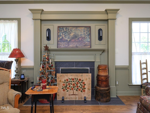 living area featuring a healthy amount of sunlight, a tiled fireplace, and wood finished floors