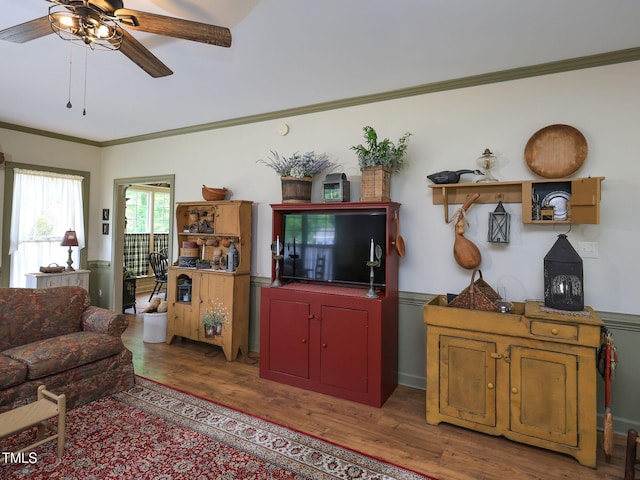living area with ceiling fan, crown molding, and wood finished floors