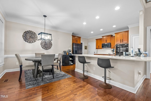 200 Heather Brook Cir, Spring Lake, NC 28390 - kitchen featuring brown cabinets, a peninsula, dark wood-type flooring, visible vents, and black appliances