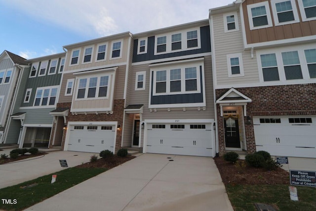 multi unit property featuring board and batten siding, driveway, and a garage