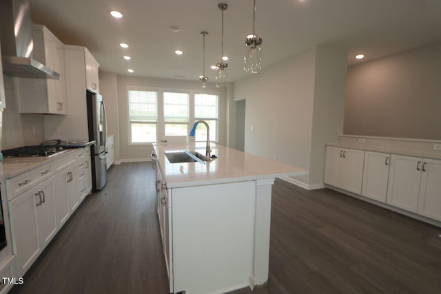 kitchen featuring freestanding refrigerator, dark wood-style floors, gas cooktop, wall chimney exhaust hood, and a sink