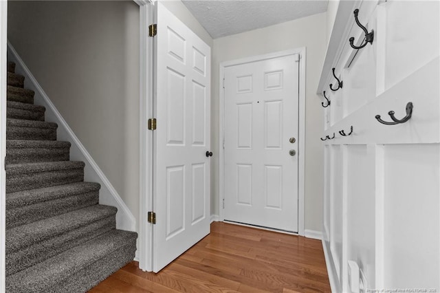 interior space with baseboards, a textured ceiling, wood finished floors, and stairway