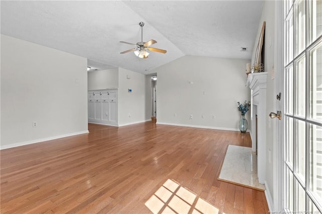 unfurnished living room featuring lofted ceiling, baseboards, ceiling fan, a textured ceiling, and light wood-style flooring