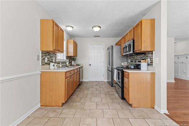 kitchen featuring baseboards, decorative backsplash, and appliances with stainless steel finishes