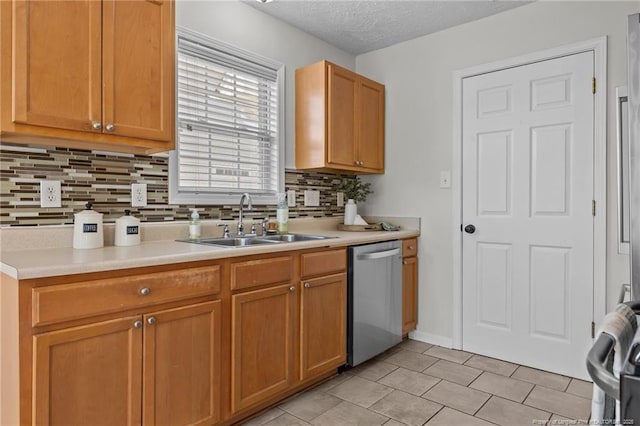 kitchen with a sink, backsplash, dishwasher, and light countertops