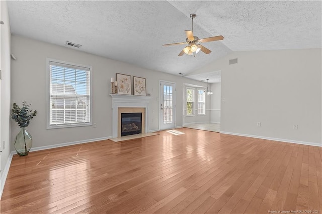 unfurnished living room with a textured ceiling, visible vents, and ceiling fan with notable chandelier