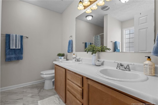 bathroom featuring double vanity, toilet, a sink, and marble finish floor
