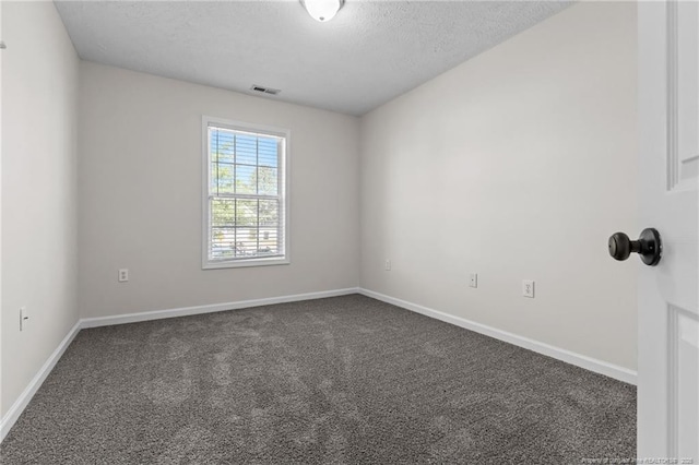 spare room with visible vents, a textured ceiling, baseboards, and dark colored carpet