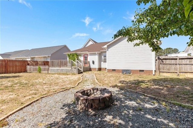 back of house with a fenced backyard, a wooden deck, an outdoor fire pit, and crawl space