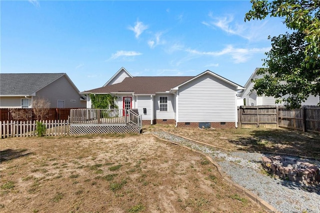back of house with a wooden deck, a fenced backyard, crawl space, an outdoor fire pit, and a yard