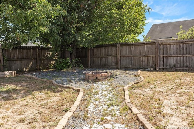 view of yard featuring a fenced backyard and a fire pit
