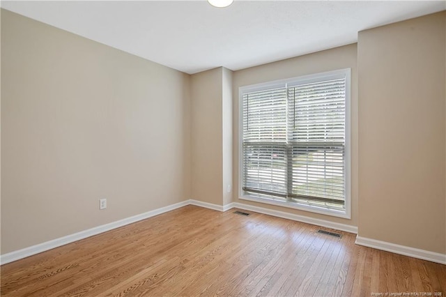 unfurnished room featuring baseboards, wood finished floors, and visible vents